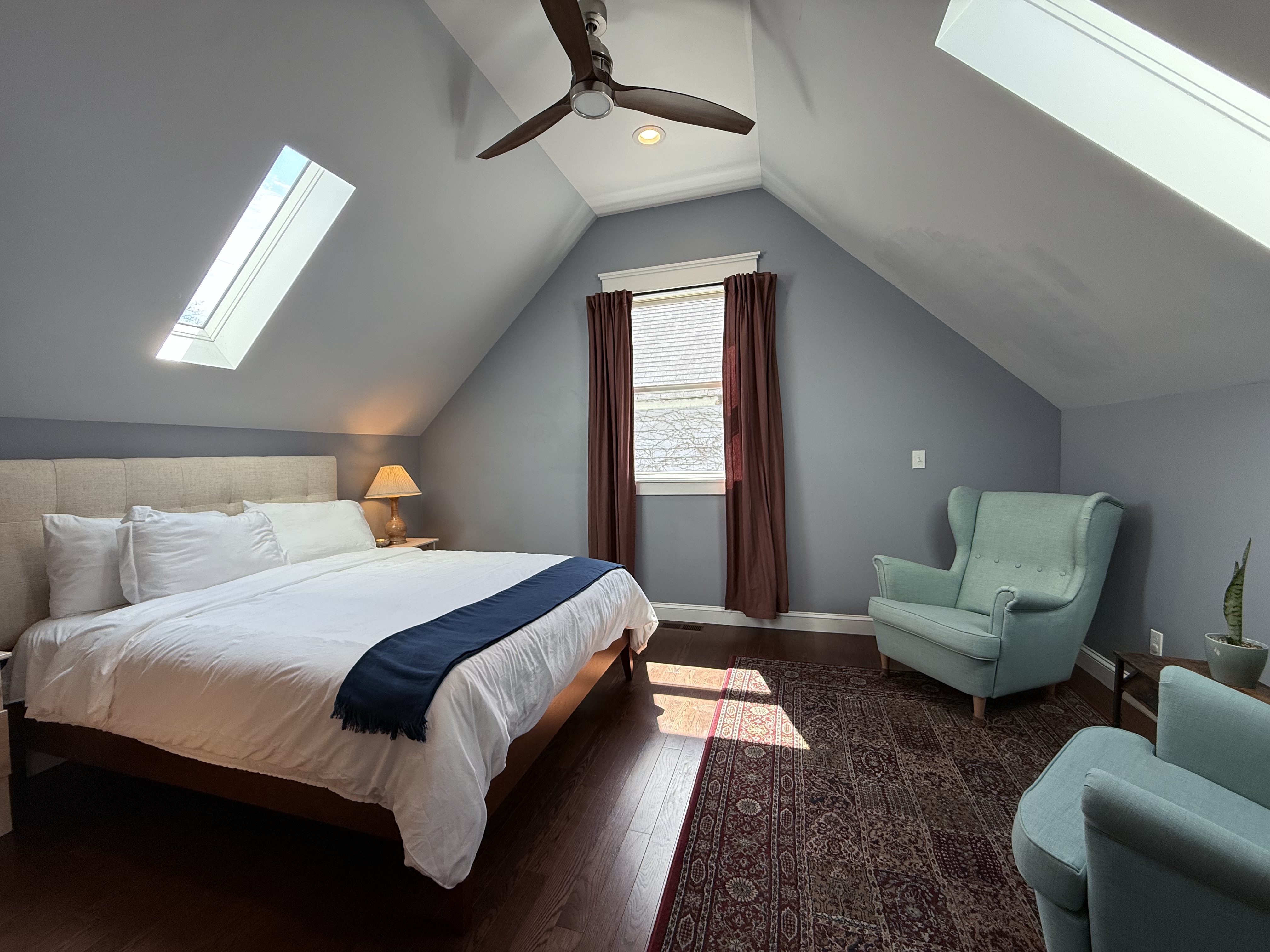 The Fifth — master bedroom with dual skylights and mint wing chairs