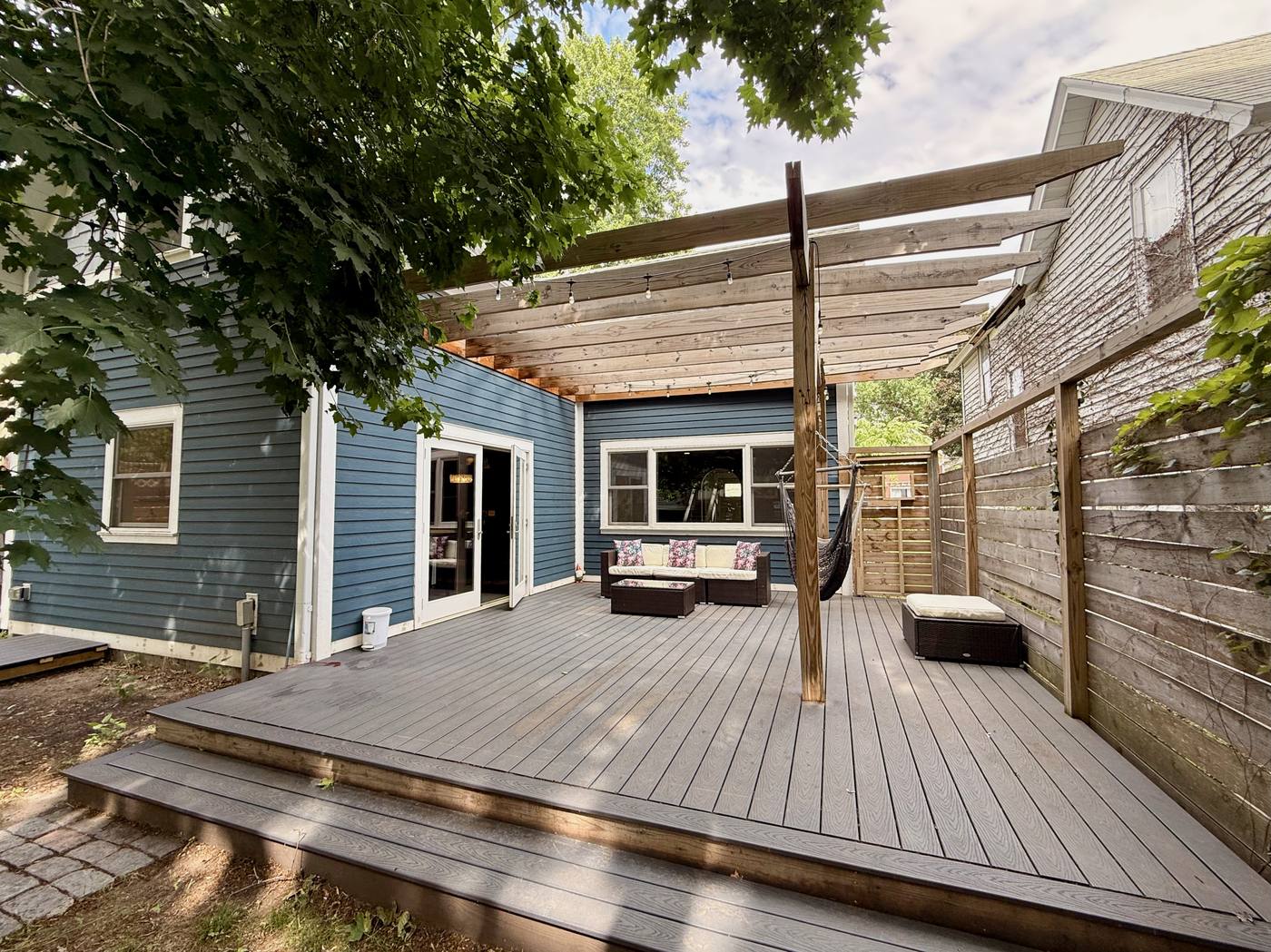 Full deck exterior with pergola and summer greenery